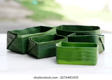 Handcrafted rectangular food containers made from fresh banana leaves, eco-friendly and biodegradable. Concept of natural packaging, Thai traditional wisdom, zero waste lifestyle,  sustainable living.