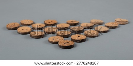 Handcrafted rustic coconut shell buttons on grey background close up