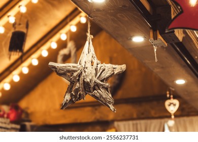 A handcrafted wooden star hangs from the ceiling, illuminated by soft glowing lights. The background reveals a warm, inviting atmosphere perfect for celebrating winter festivities. - Powered by Shutterstock