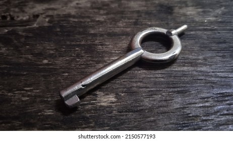 A Handcuff Key Placed On A Wooden Table