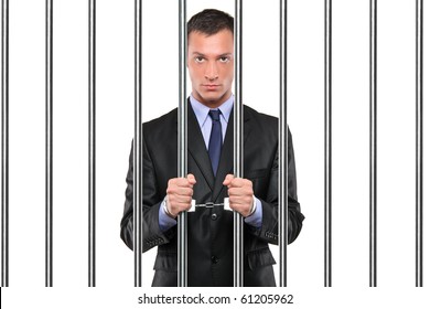 A handcuffed businessman in jail holding bars isolated on white
