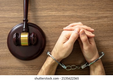 Handcuffed Convict, Law offender and Justice. Court sentence Prison. Handcuff locked and judge gavel on a wooden table, top view. 

