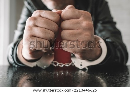 handcuffed hand is strapped inside interrogation room. the concept of arrest and incarceration. A prisoner in prison. interrogation in prison. criminal is being interrogated. conducting interrogations
