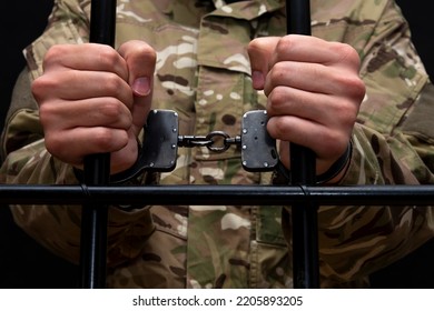 A Handcuffed Soldier Behind The Bars Against A Black Background. Concept: Court Martial, Refusal To Mobilize, Crime In The Army.
