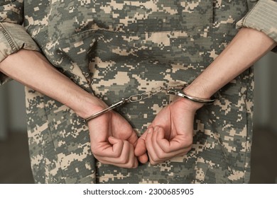 Handcuffed soldier in military army clothes. Close up of hands in handcuffs