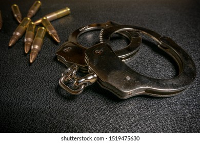 Handcuffs and ammo on a black table. Arms trade, crime concept