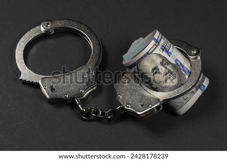 Handcuffs with dollar banknotes on dark background. Sanctions concept.