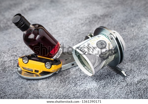 Handcuffs with dollars, car and bottle. Drunk\
driving warning\
concept