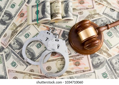 handcuffs, judge's hammer against the background of dollar bills. - Shutterstock ID 1034710060