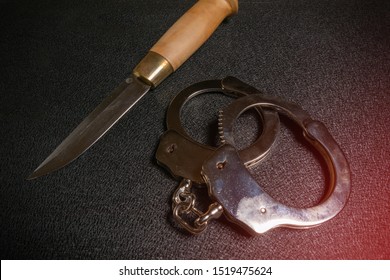 Handcuffs And Knife On A Black Table. Violence, Murder, Street Gang Concept