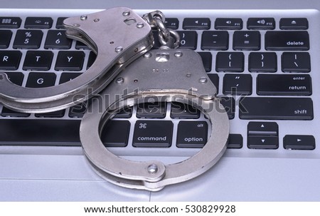 Handcuffs on keyboard, symbolizing cyber crime
