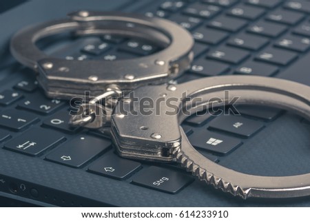 Handcuffs on the laptop close-up. Cyber hacker crime concept.