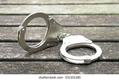 Handcuffs On Wooden Background. Criminal Justice 