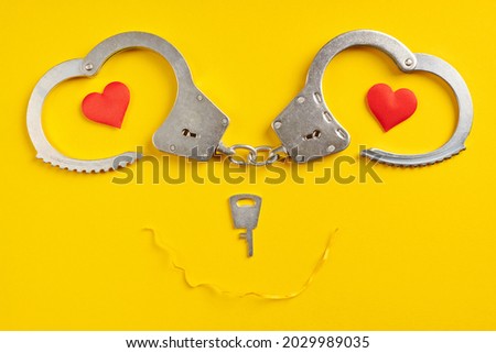 Handcuffs smile shape on yellow background. Freedom concept. Imprisonment, deprivation of liberty and apprehend perpetrators.