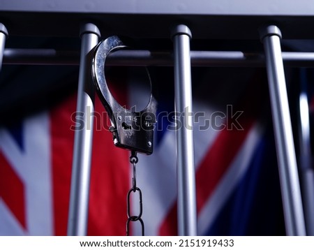 Handcuffs swing on prison bars with Union jack British flag background close up dolly shot slow motion selective focus