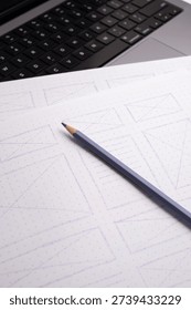 Hand-Drawn Website Wireframes Close-up on Dot-Grid Paper with Pencil and Laptop Keyboard