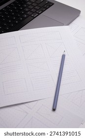 Hand-Drawn Website Wireframes Close-up on Dot-Grid Paper with Pencil and Laptop Keyboard