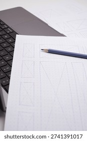 Hand-Drawn Website Wireframes Close-up on Dot-Grid Paper with Pencil and Laptop Keyboard