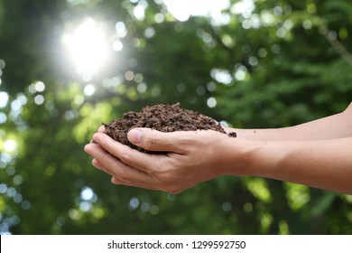 Handful of arable soil in hands of responsible farmer, close up, selective focus - Shutterstock ID 1299592750