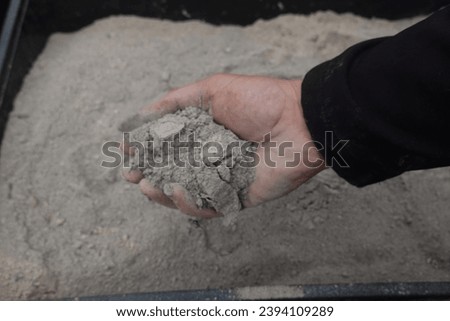 a handful of ashes to use in the garden. man holding a pile of wood ashes