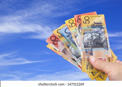 Handful Of Australian Money With Blue Sky Background.