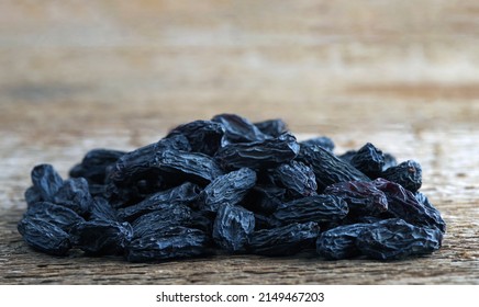 A Handful Of Large Blue Raisins On A Woody Texture Background. Selective Focus.	
