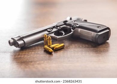 Handgun and bullets on the wooden table.