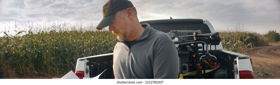 HANDHELD 50s Caucasian Male Farmer Looking Through The Papers While Sitting On The Back Of His Truck