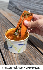 Handheld Birria Taco Dipped Into A Side Of Consomme