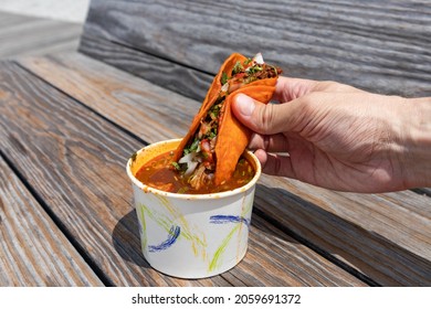 Handheld Birria Taco Dipped Into A Side Of Consomme