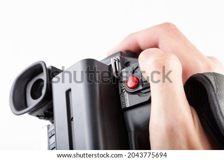 Handheld camcorder, old retro video camera object held in hand, closeup, white background, cut out. Finger on the red rec record button. Filmmaking, movie making abstract concept, first person pov