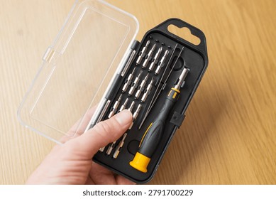 Handheld compact precision screwdriver bit set with transparent lid and yellow grip for electronics repair and portable diy toolkit background for banner.