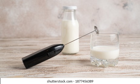 Handheld Drink Mixer. Black Milk Frother And Milk In Bottle And Glass On Wooden Table