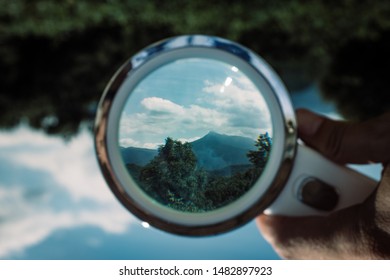 Handheld Loupe optical magnification effects view upside down on a green and blue nature landscape - Shutterstock ID 1482897923
