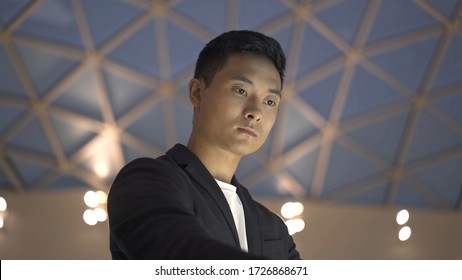 Handheld Portrait Shot Of Young Asian Man Dressed In Jacket And White Shirt Searching For Information In Interactive Wayfinding Kiosk Shot From Below