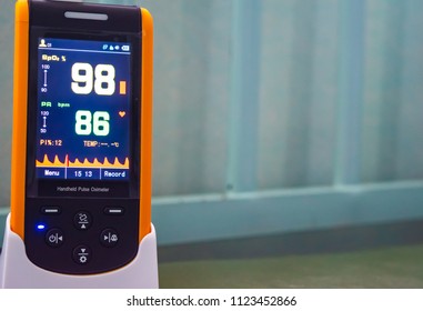 Handheld Pulse Oximeter,medical Device Use To Monitor Blood Oxygen In Patient In The Emergency Room At Hospital, Showing Normal Blood Oxygen Ninety-eight In Yellow And Pulse Rate Eighty-six In Green. 