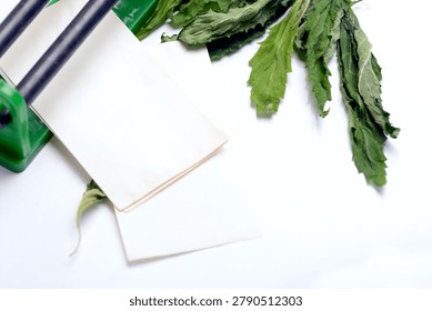 Handheld rolling tool with paper sheets and dried green herbal leaves for smoking on white background.