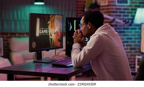 Handheld shot of gamer streaming multiplayer first person shooter angry after losing online tournament on gaming pc. African american man playing internet action game upset after failing level. - Shutterstock ID 2190245509