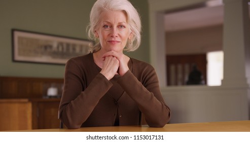 Handheld Shot Of Senior Woman Homeowner Sitting At Dining Room Table