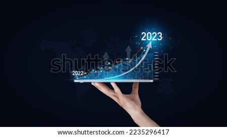 Hand-holding tablet and showing arrow graph corporate to planning businesses finance and investment challenges, and business strategy.Goals and Visions to success for corporate future in 2023