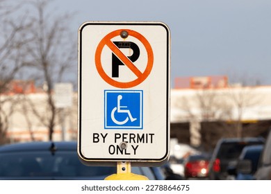 A handicap parking restriction sign with a blue wheelchair symbol in a retail shopping plaza.