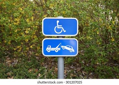 A handicap parking sign and car removal sign on green background - Powered by Shutterstock