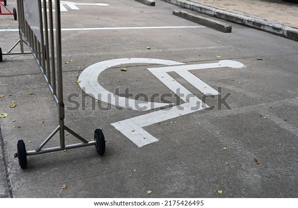 The handicap\
parking sign is painted white on the road with a steel (stainless\
steel) traffic barrier and black wheels across. Special parking\
space reserved for\
wheelchairs.