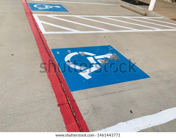 Handicap parking space with the paint chipping\
away on concrete.