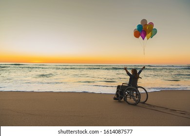 Handicapped man on a wheelchair with colored balloons at the beach - Powered by Shutterstock