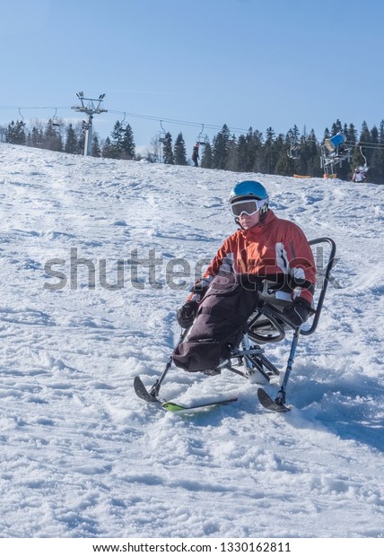 handicapped man riding a mono ski from the\
mountains, adaptive skiing and winters holiday for disabled men,\
vacation in the\
mountains