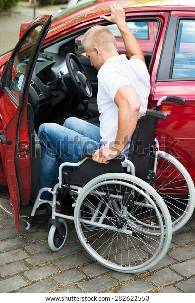 Handicapped\
Man Sitting On Wheelchair Boarding In His\
Car