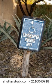 Handicapped Parking Sign With Figure In Wheelchair Wearing Western Style Cowboy Or Ten Gallon Hat With Cactus In The Background