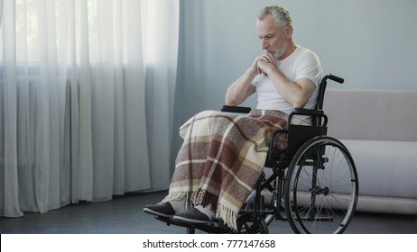 Handicapped person sitting in wheelchair and thinking about life, depression
