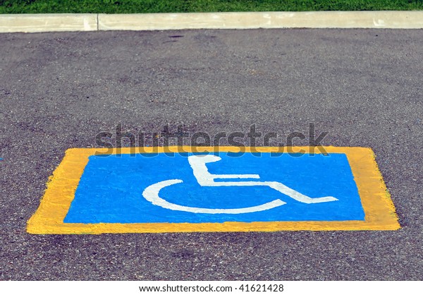 Handicapped\
reserved parking sign painted on\
pavement.